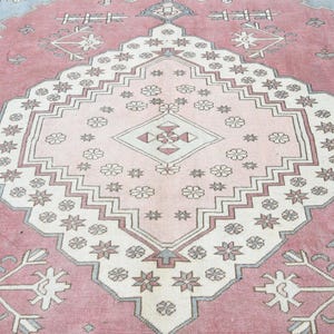 May include: A pink and white patterned rug with a central diamond shape. The rug has a traditional design with intricate details.