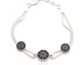 May include: A silver bracelet with three round black and silver charms. The charms have a decorative design.