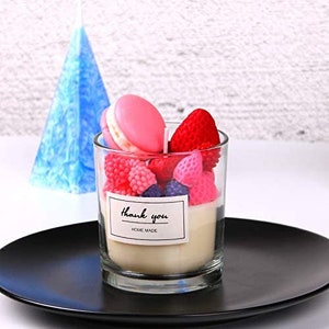 Puede incluir: Un tarro de vidrio transparente lleno de velas de colores con forma de macarons, fresas y frambuesas. El tarro tiene una etiqueta blanca que dice "Gracias Hecho en casa".