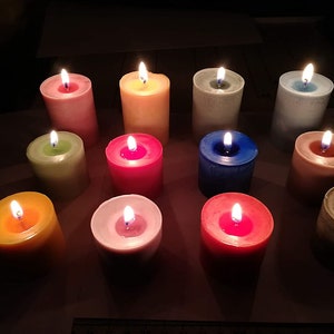Puede incluir: Una colecci&oacute;n de 12 velas coloridas, cada una con un tono diferente, incluyendo amarillo, verde, rosa, rojo, azul y blanco. Las velas est&aacute;n todas encendidas y proyectan un brillo c&aacute;lido.