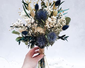 May include: A dried flower bouquet with blue thistle, white baby's breath, and dried grasses. The bouquet is tied with twine.