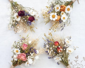 May include: Four small bouquets of dried flowers, each tied with twine. The bouquets feature a variety of dried flowers, including white daisies, purple lavender, and pink and red roses.