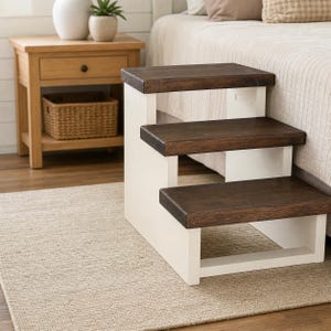 May include: A three-step pet staircase featuring white painted side supports and dark brown stained wooden treads. The structure is designed with a tiered configuration, providing three distinct levels for climbing, with a solid, sturdy frame.