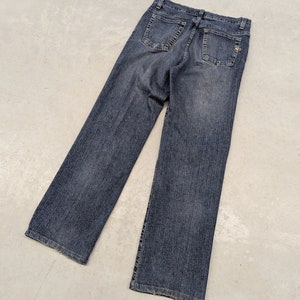 Peut inclure: Un jean en denim bleu foncé avec un aspect délavé. Le jean a une jambe droite et un style classique à cinq poches.