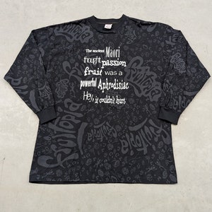 May include: Black long-sleeve shirt with a white print that reads "The ancient Maori thought passion fruit was a powerful Aphrodisiac. Hey, it couldn't hurt."
