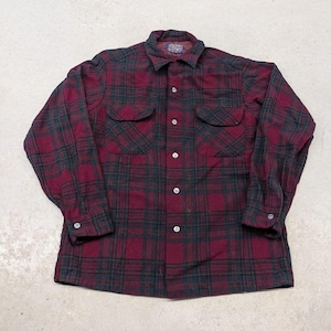 Puede incluir: Una camisa de manga larga con botones y un patrón de cuadros en rojo oscuro y negro. La camisa incluye un cuello estándar, dos bolsillos en el pecho con solapas abotonadas y puños con botones. Una pequeña etiqueta azul es visible en el cuello.
