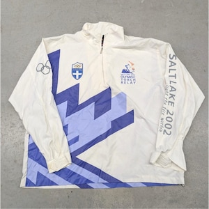 May include: A white and blue Salt Lake 2002 Olympic Torch Relay jacket. The jacket features a half-zip closure, long sleeves, and a geometric design in blue. The text "SALT LAKE 2002" is printed on the right sleeve.