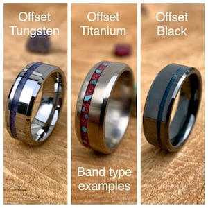 May include: Three different types of wedding bands with offset inlays. The bands are made of tungsten, titanium, and black metal. The inlays are made of different materials, including purple, red, and blue. The text "Offset Tungsten", "Offset Titanium", and "Offset Black" is displayed above each band. The text "Band type examples" is displayed below the bands.
