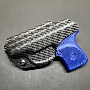 May include: A blue Ruger pistol with a black carbon fiber holster. The holster has a screw on the bottom.