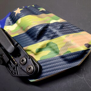 May include: A black and blue gun holster with a camouflage pattern and a star design. The holster is made of a durable material and has a secure fit.