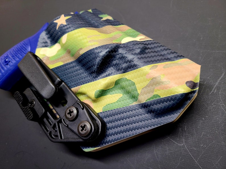 May include: A black and blue gun holster with a camouflage pattern and a star design. The holster is made of a durable material and has a secure fit.