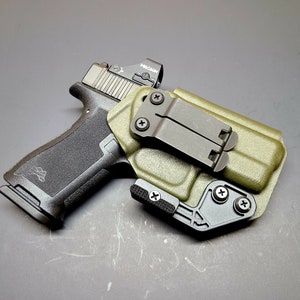 May include: A green and black gun holster with a black handgun and a red dot sight. The sight has the word "HOLOSUN" printed on it.