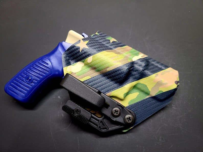 May include: A blue and black handgun holster with a camouflage pattern. The holster has a black clip and a star on the side.
