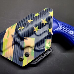 May include: A blue and black gun holster with a camouflage and American flag pattern. The holster is made of a durable material and has a secure fit.