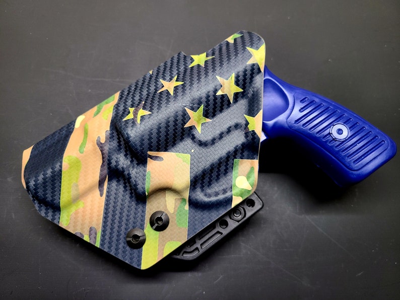 May include: A blue and black gun holster with a camouflage and American flag pattern. The holster is made of a durable material and has a secure fit.