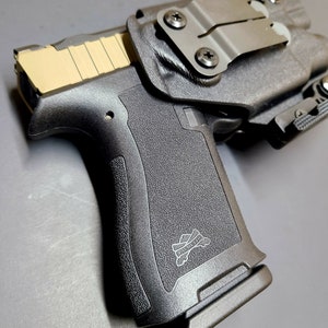 May include: A black handgun with a tan slide and a black holster. The holster has a metal clip and a black strap. The handgun has a black grip with a logo that says "Palmetto State Armory".