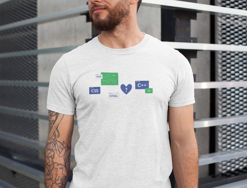 K&ouml;nnte beinhalten: Ein wei&szlig;es T-Shirt mit einem Grafikdesign aus verschiedenen Programmiersprachen, darunter PHP, CSS, HTML und C++. Die Grafik enth&auml;lt ein Herz mit einem Fragezeichen darin.