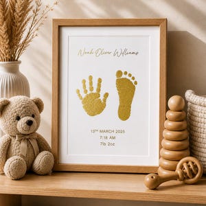 May include: A framed print with a baby's handprint and footprint in gold ink. The print includes the baby's name, date, time, and weight: 7lb 2oz. A teddy bear, wooden toys, and a woven basket are on the shelf.