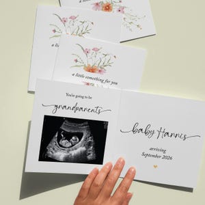 May include: White announcement cards with floral designs. One card features an ultrasound image and the text "You're going to be grandparents." Another card reads "baby Harris arriving September 2026."