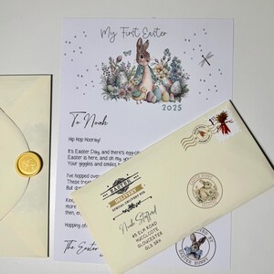 May include: A white envelope with a bunny rabbit illustration and the text "Easter Bunny Delivery" in a gold circle. The envelope is addressed to Noah Stafford at 45 Elm Road, Hucclecote, Gloucester, GL3 3RH. The envelope has a gold wax seal and a stamp with a red and yellow design.