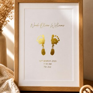 May include: A framed print with a light wood frame. The print features gold foil footprints and the name "Noah Oliver Williams". Below the name are the date, time, and weight: 13th March 2025, 7:18 AM, 7lb 2oz.
