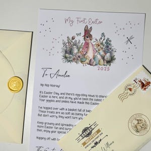 May include: A white card with a pink bunny rabbit illustration and the text "My First Easter" and "To Amelia". The card has a pink and white floral design and the year 2025.