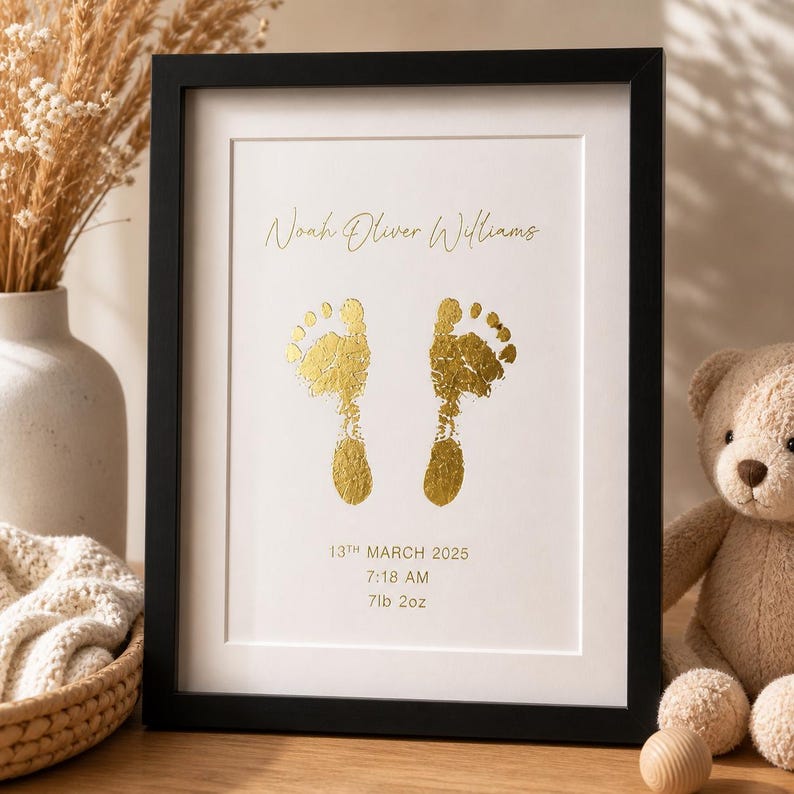 May include: Framed print with gold foil baby footprints. The print includes the name "Noah Oliver Williams", the date "13th March 2025", time "7:18 AM", and weight "7lb 2oz". The frame is black.