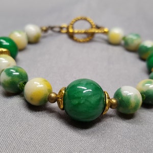 Pulsera* en color verde y amarillo (20 cm de largo) realizada con piedras de jade de 8 mm, cerámica marmolada de 12,10 mm, cuentas de vidrio de 3 mm con elementos decorativos de metal.