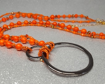 Orangefarbene Halskette (Länge 78 cm + 5 cm) aus kugelförmigen Howlithsteinen, Glasperlen und zwei oxidierten Metalldrahtring (5-, 2,5-cm).