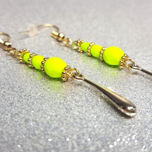 Boucles d&#39;oreilles de couleur vert fluo d&#39;une longueur totale de 6,5 cm (longueur de chute 4,5 cm) composées de perles de verre et d&#39;éléments décoratifs.