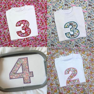 May include: A collection of white t-shirts featuring embroidered numbers on the front. The numbers are filled with various floral and animal patterns, including a red floral three, a jungle animal three, a floral four in a hoop, and a floral two.