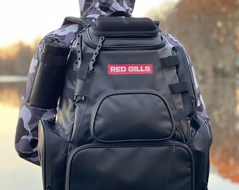 May include: A black fishing backpack with a red logo that says "RED GILLS". The backpack has multiple pockets and compartments.