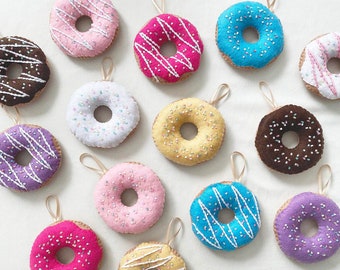 May include: Twelve felt donuts with different colored glazes and sprinkles. The donuts are all hanging from strings.