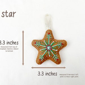 May include: A brown felt star ornament with a white snowflake design and red and green beads. The star is 3.3 inches wide and 3.3 inches tall.
