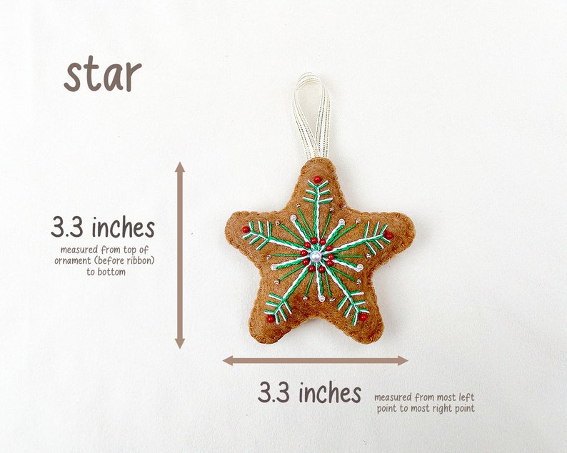 May include: A brown felt star ornament with a white snowflake design and red and green beads. The star is 3.3 inches wide and 3.3 inches tall.
