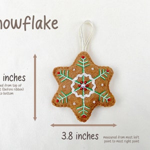 May include: A brown felt snowflake ornament with green and white embroidery, red beads, and a white loop for hanging. The ornament measures 3.8 inches in diameter.