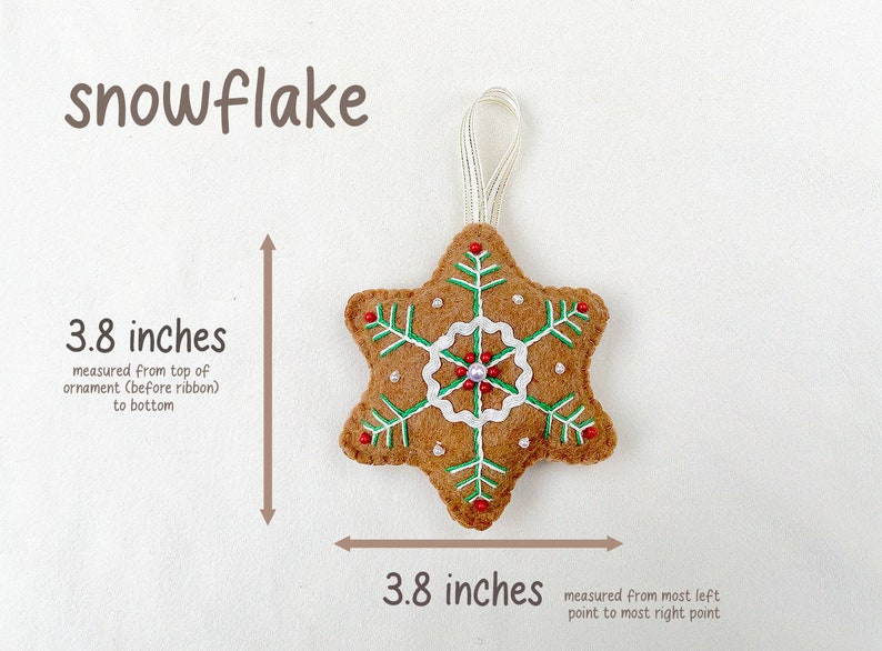 May include: A brown felt snowflake ornament with green and white embroidery, red beads, and a white loop for hanging. The ornament measures 3.8 inches in diameter.