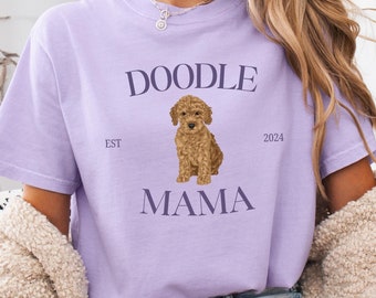 May include: A lavender t-shirt with the text "Doodle Mama" and a brown doodle dog illustration. The text "Est 2024" is also on the shirt.