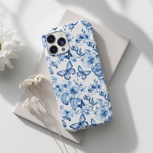 May include: A white phone case with a blue and white floral pattern featuring butterflies. The case has a camera lens cutout.
