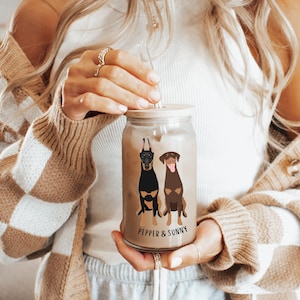 May include: A clear glass jar with a wooden lid and a straw. The jar has a black and brown illustration of two dogs with the text "Pepper & Sunny" on the bottom.