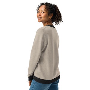 May include: A heather grey sweatshirt with black trim around the neck, cuffs, and hem. The sweatshirt is made of a soft, comfortable fabric.
