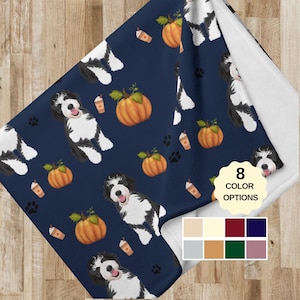 May include: A navy blue fleece blanket with a repeating pattern of white and black dogs, pumpkins, and coffee cups. The blanket has 8 color options.