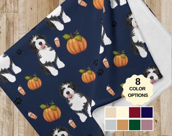 May include: A navy blue fleece blanket with a repeating pattern of white and black dogs, pumpkins, and coffee cups. The blanket has 8 color options.