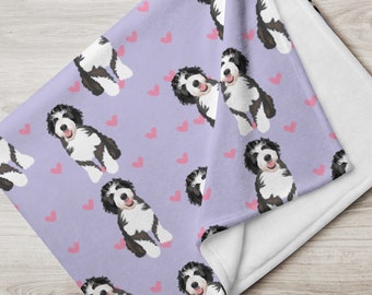 May include: A soft, purple fleece blanket with a repeating pattern of black and white dogs and pink hearts. The blanket is folded in half, showing the white fleece backing.