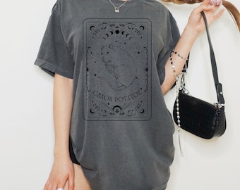 May include: A gray oversized t-shirt with a black graphic of a rat in a circle with the text "Chaos Potatoe" inside. The graphic is surrounded by a decorative border.