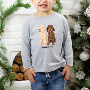 May include: A gray long-sleeve shirt with a graphic of two dogs, one brown and one cream, with the text "Brandi & Remi" printed below the dogs.