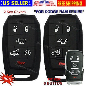 May include: Two black key covers with white icons and red accents, designed for a Dodge Ram series. The key covers have multiple buttons and are labeled "2 Key Covers". The image also includes a key fob.
