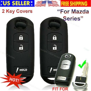May include: Black key covers for Mazda series vehicles. The image shows two key covers with lock and unlock symbols, and a separate key fob with the Mazda logo. The text "HOLD" is visible on the key covers.