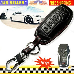 May include: Black leather car key fob cover with red stitching, a metal clasp, and a key ring. The cover has embossed buttons and a matching key fob. A white car is in the background.