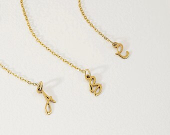 May include: Three gold-toned metal chains, each featuring a single dangling letter charm in a cursive script font. The letters A, B, and C are suspended from delicate link chains, creating a set of individual jewelry pieces with a polished finish.